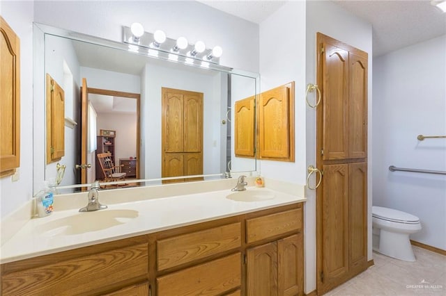 bathroom featuring toilet, tile patterned floors, a sink, and double vanity