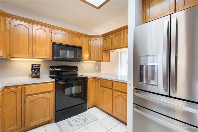 kitchen featuring light tile patterned floors, brown cabinetry, light countertops, and black appliances