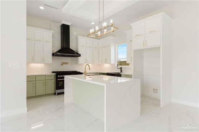 kitchen featuring high end black range oven, decorative light fixtures, an island with sink, white cabinets, and wall chimney range hood