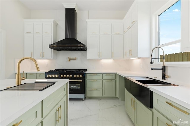 kitchen featuring wall chimney range hood, sink, backsplash, high end black range, and green cabinetry