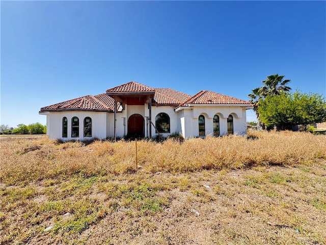 mediterranean / spanish house with a tile roof and stucco siding