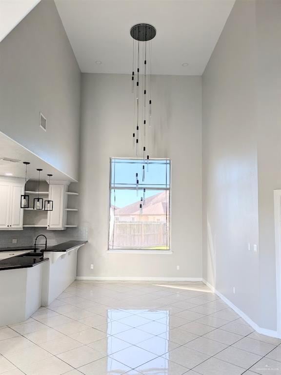 kitchen with backsplash, white cabinetry, light tile patterned flooring, and pendant lighting