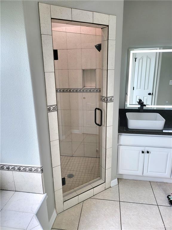 bathroom with tile patterned flooring, vanity, and an enclosed shower