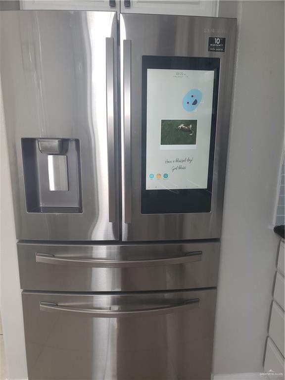 room details with white cabinets and stainless steel fridge