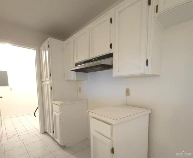 kitchen with light tile patterned floors and white cabinetry