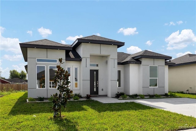 2012 Trinity St, Donna, TX 78537 - prairie-style house with stucco siding, fence, a shingled roof, and a front lawn
