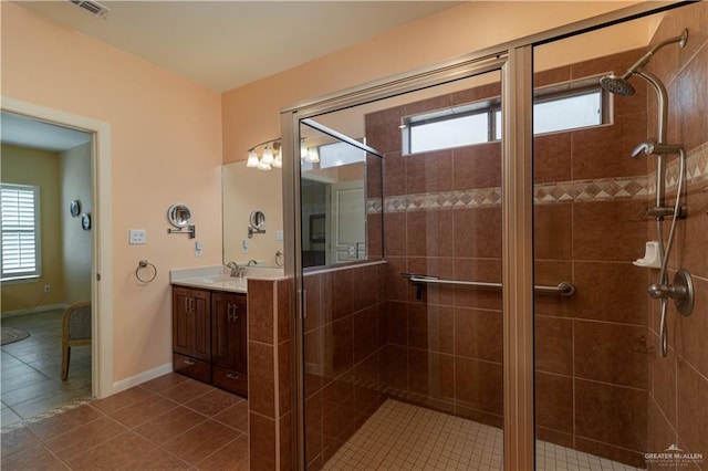 bathroom with tile patterned flooring, vanity, a healthy amount of sunlight, and an enclosed shower