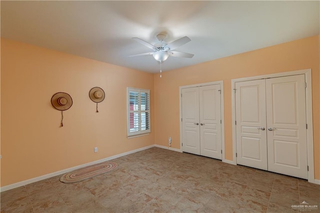 unfurnished bedroom with ceiling fan and two closets