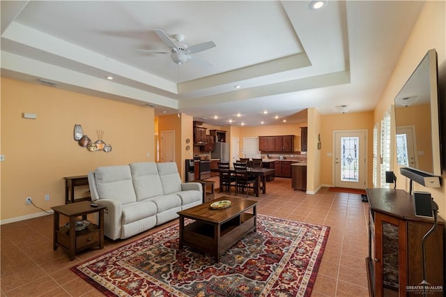 living room featuring light tile patterned floors, a raised ceiling, and ceiling fan