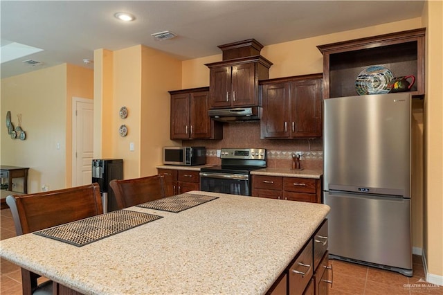 kitchen featuring light tile patterned floors, tasteful backsplash, dark brown cabinets, stainless steel appliances, and extractor fan