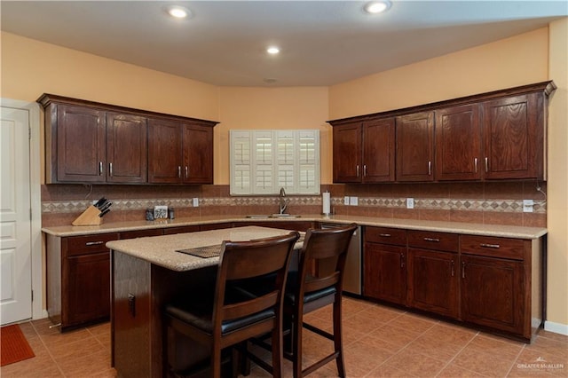 kitchen featuring sink, a breakfast bar area, decorative backsplash, dark brown cabinets, and a kitchen island