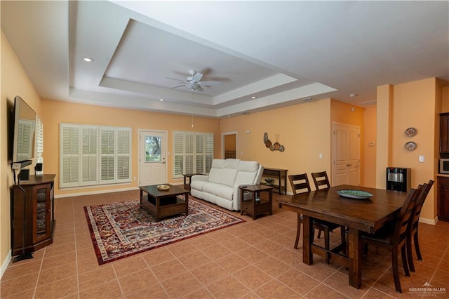 interior space featuring light tile patterned floors, a raised ceiling, and ceiling fan