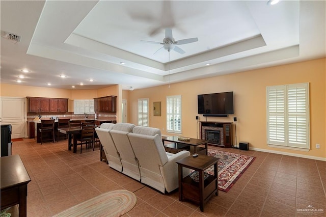 tiled living room featuring a tray ceiling and ceiling fan