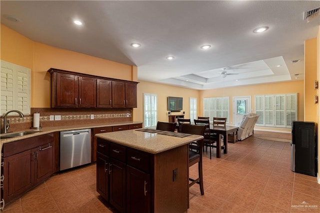 kitchen with dishwasher, a raised ceiling, a kitchen island, and a wealth of natural light