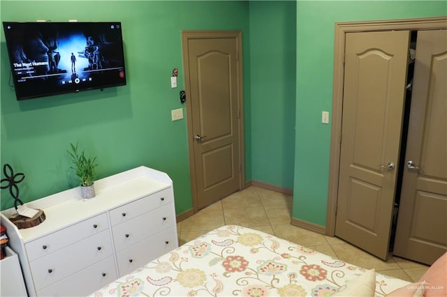 bedroom featuring light tile patterned floors, a closet, and baseboards