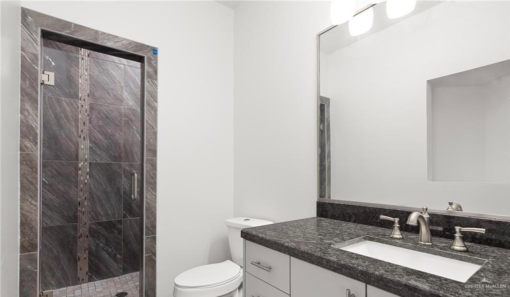 bathroom featuring vanity, toilet, and a shower with shower door