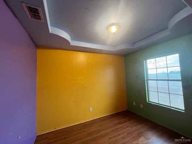 unfurnished room featuring a tray ceiling and hardwood / wood-style floors