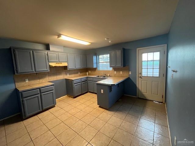 kitchen with tasteful backsplash, gray cabinets, sink, and light tile patterned floors