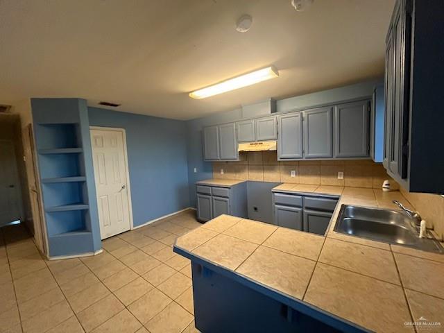 kitchen with sink, light tile patterned floors, tasteful backsplash, tile countertops, and kitchen peninsula