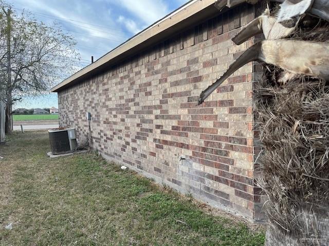 view of side of property featuring a yard and central AC unit