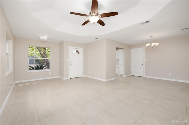 tiled empty room with a raised ceiling and ceiling fan with notable chandelier