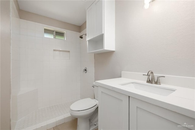 bathroom with tiled shower, vanity, and toilet