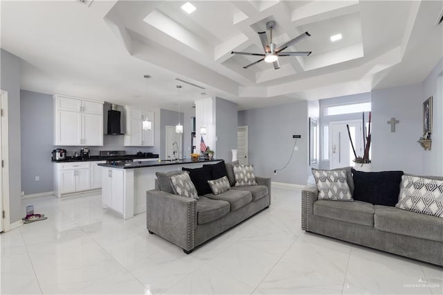 living room with coffered ceiling, ceiling fan, and a tray ceiling