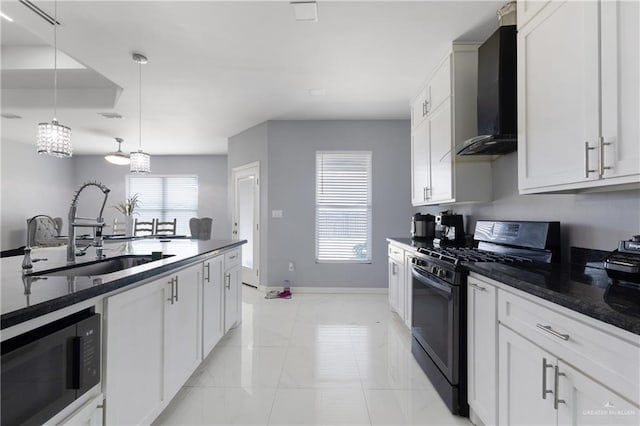 kitchen featuring gas stove, built in microwave, white cabinetry, wall chimney exhaust hood, and decorative light fixtures