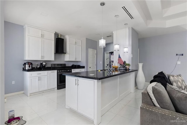 kitchen featuring white cabinetry, sink, wall chimney range hood, stainless steel range oven, and pendant lighting