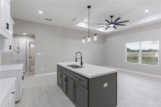 kitchen with ceiling fan, sink, an island with sink, pendant lighting, and white cabinets