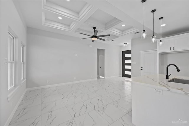 kitchen with marble finish floor, coffered ceiling, a sink, and baseboards