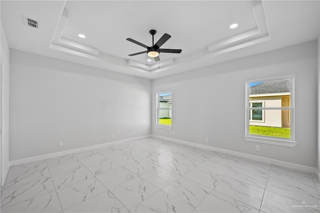 unfurnished room featuring a tray ceiling, marble finish floor, recessed lighting, visible vents, and baseboards