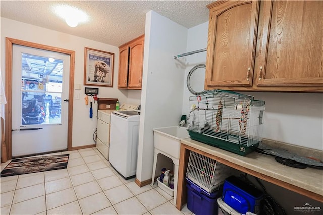 laundry room with washer / dryer, light tile patterned floors, cabinet space, and a textured ceiling