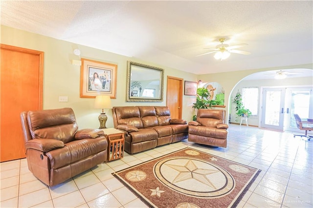 living area with a ceiling fan, arched walkways, a textured ceiling, and light tile patterned floors