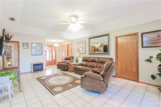 living room featuring light tile patterned floors, a textured ceiling, visible vents, and a ceiling fan