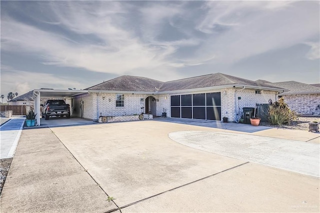 view of front facade featuring a carport, concrete driveway, brick siding, and fence