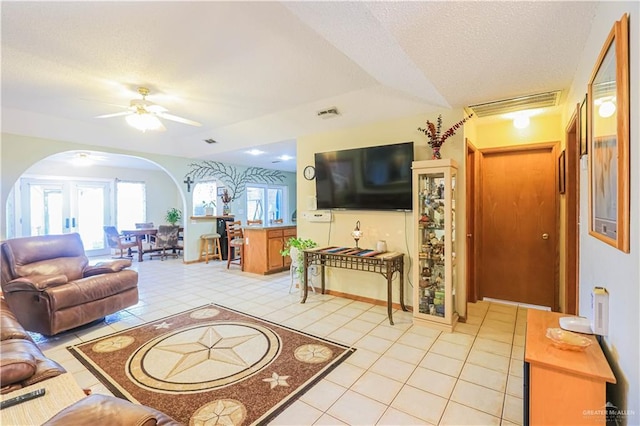 living room featuring arched walkways, visible vents, a textured ceiling, and light tile patterned flooring