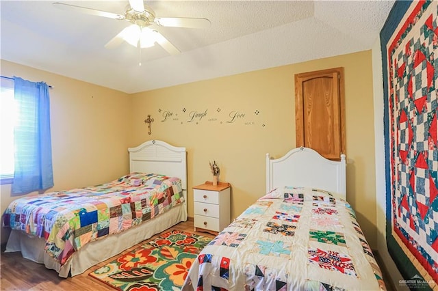 bedroom with a ceiling fan, a textured ceiling, and wood finished floors