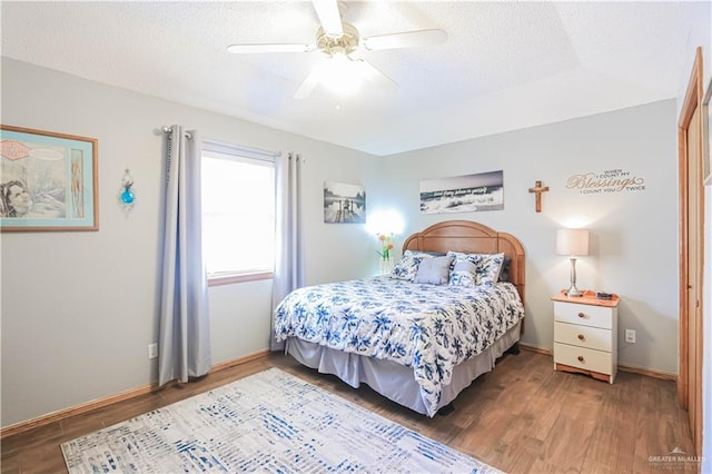 bedroom with a textured ceiling, ceiling fan, wood finished floors, and baseboards