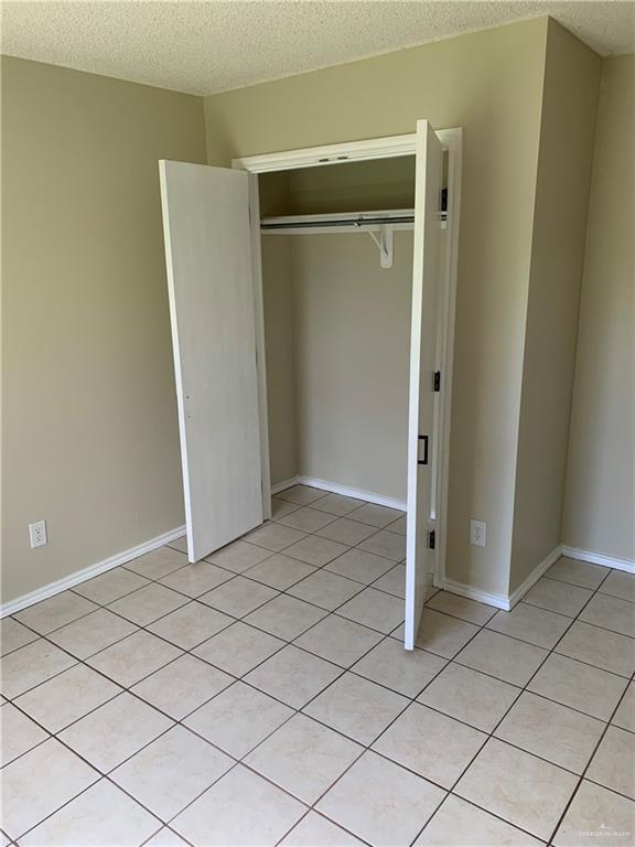 unfurnished bedroom with a closet, light tile patterned flooring, and a textured ceiling