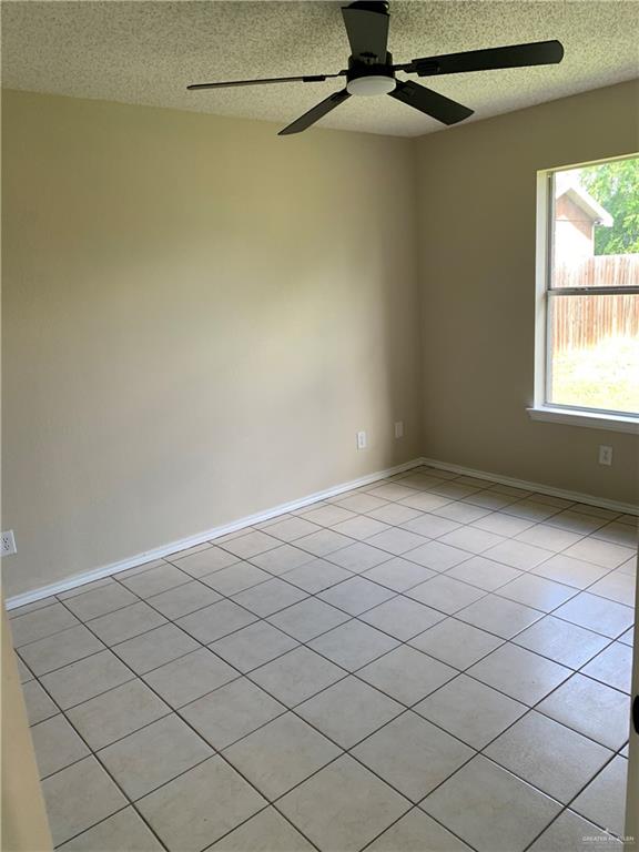 spare room featuring ceiling fan, light tile patterned floors, and a textured ceiling