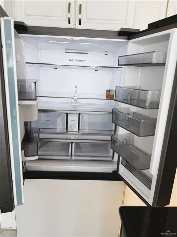 room details featuring white cabinetry and fridge