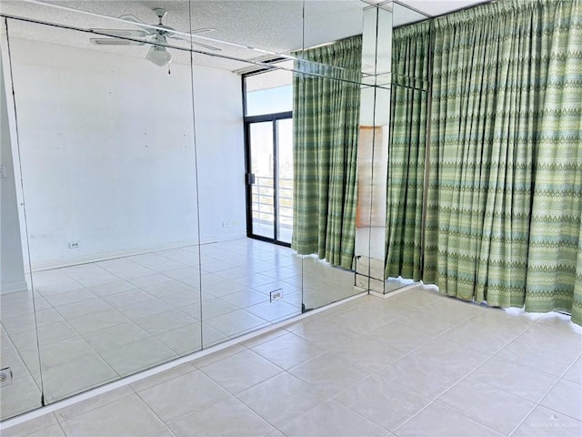 unfurnished room with expansive windows, light tile patterned flooring, and ceiling fan