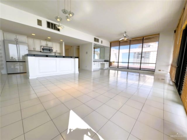 kitchen featuring hanging light fixtures, expansive windows, white cabinets, and light tile patterned flooring