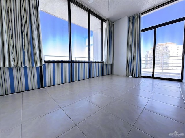 spare room with floor to ceiling windows, tile patterned floors, and a textured ceiling