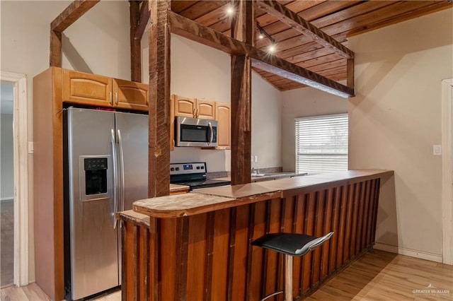 kitchen featuring kitchen peninsula, vaulted ceiling, appliances with stainless steel finishes, wood ceiling, and light wood-type flooring