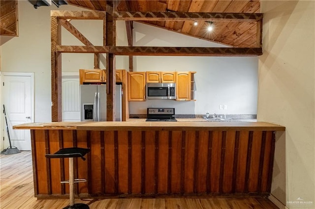 kitchen with light wood-type flooring, wood ceiling, stainless steel appliances, vaulted ceiling, and sink