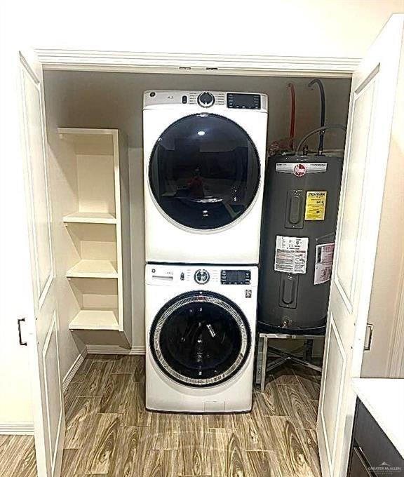 washroom featuring stacked washer / dryer and electric water heater