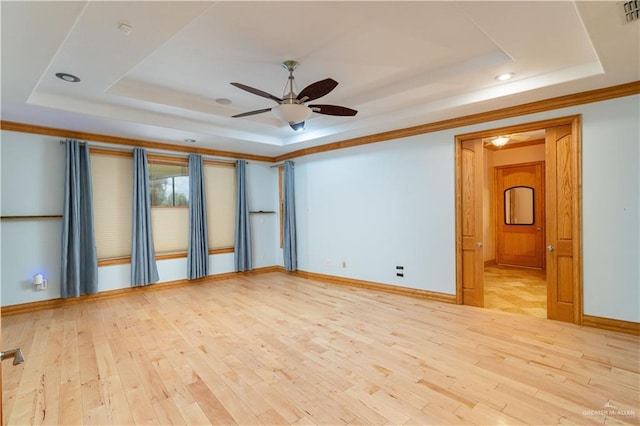 spare room featuring light hardwood / wood-style floors, a raised ceiling, ceiling fan, and ornamental molding