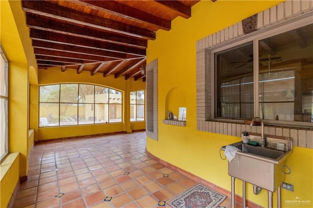 unfurnished sunroom with beam ceiling, ceiling fan, wooden ceiling, and sink